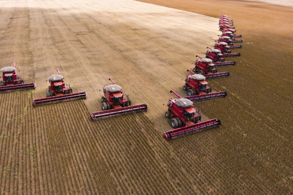 Máquinas agrícolas em plantação de soja, em texto sobre ciclos econômicos do Brasil.